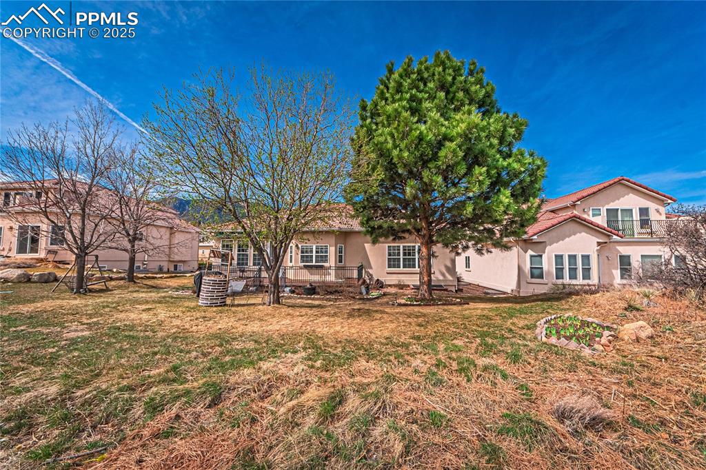 Image 46 of 49: Back of property with stucco siding and a lawn