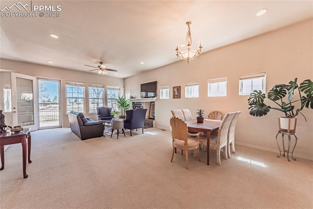 Image 6 of 49: Carpeted dining space with ceiling fan with notable chandelier, baseboards,