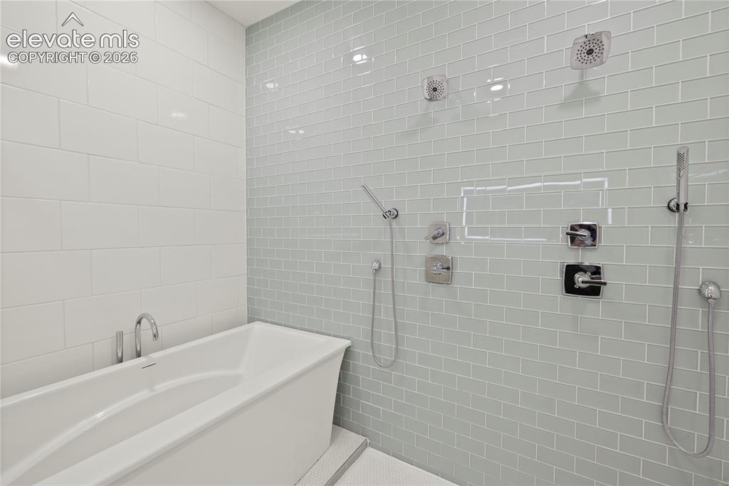 Image 24 of 49: Spa shower with 6 heads and deep soaker tub inside the enclosure