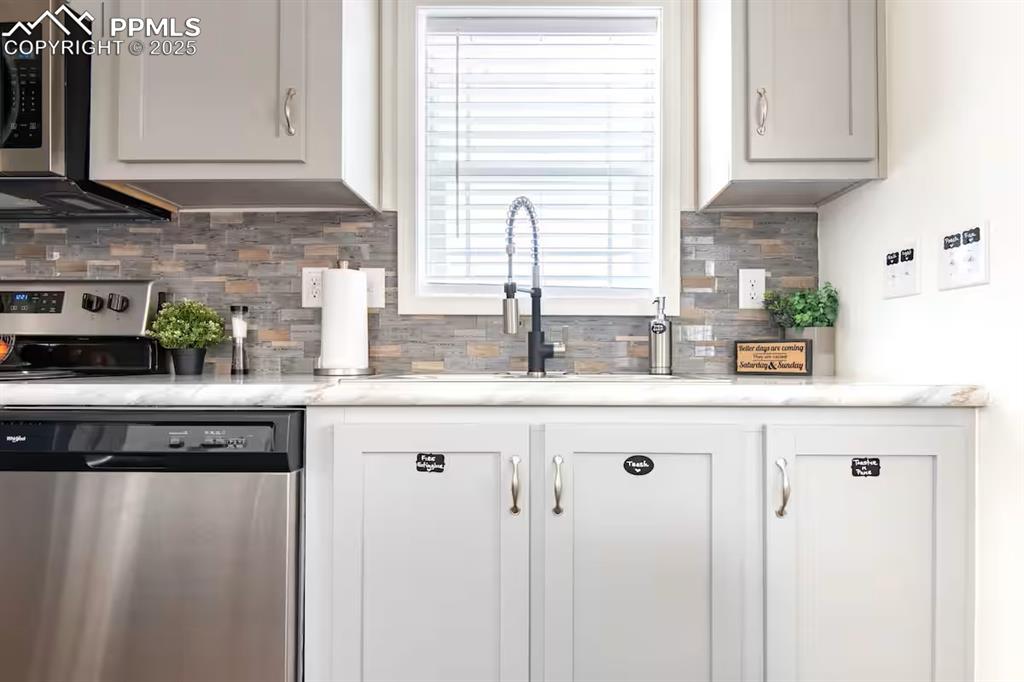 Image 11 of 27: Kitchen with appliances with stainless steel finishes, light countertops, b