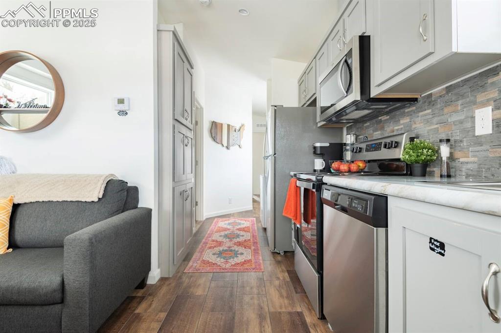 Image 14 of 27: Kitchen with stainless steel appliances, white cabinetry, light countertops