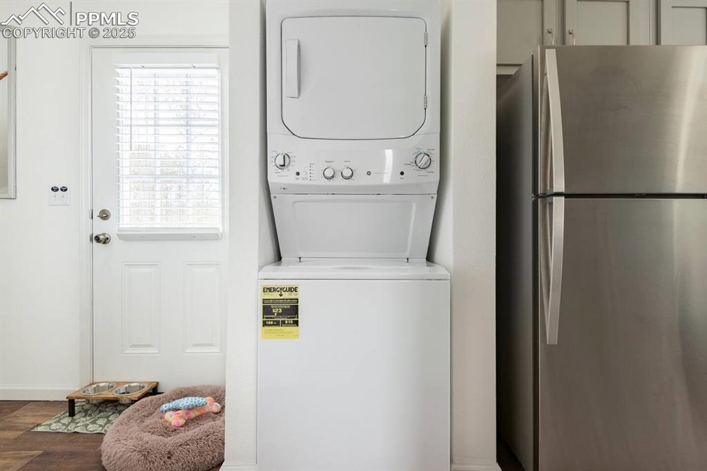 Image 16 of 27: Washroom with laundry area, stacked washing maching and dryer, and dark woo