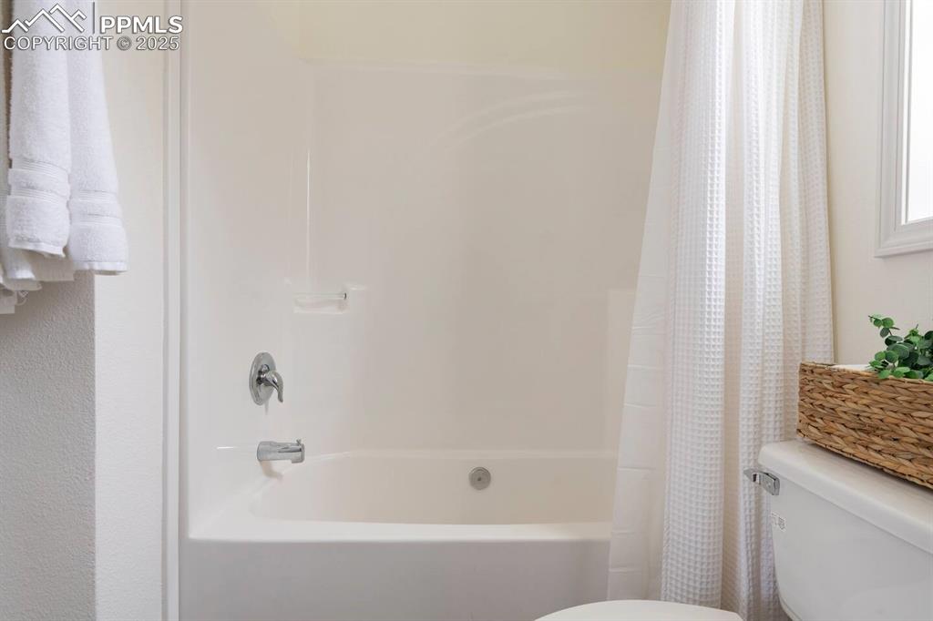 Image 21 of 27: Full bathroom with toilet and shower / bath combo with shower curtain