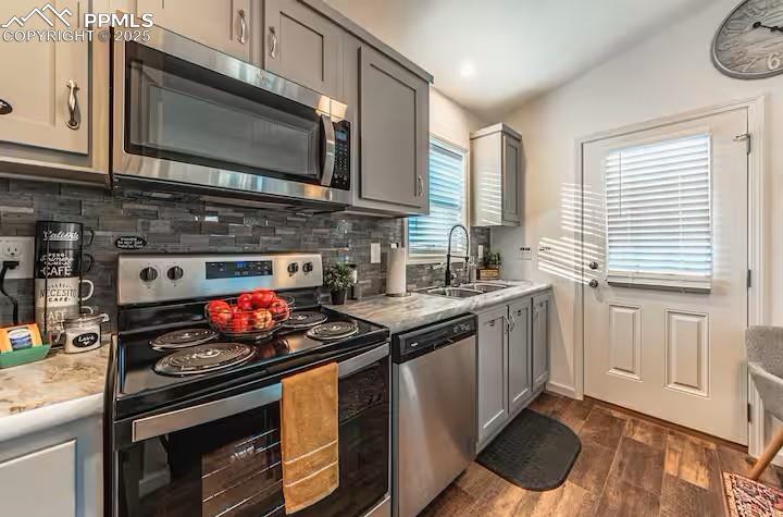 Image 7 of 27: Kitchen with decorative backsplash, gray cabinets, stainless steel applianc