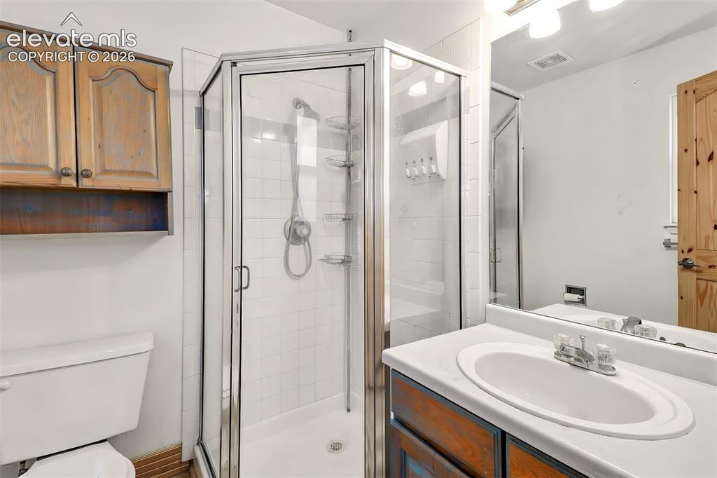 Image 11 of 34: Bathroom featuring a corner shower enclosure with tiled surround, vanity wi