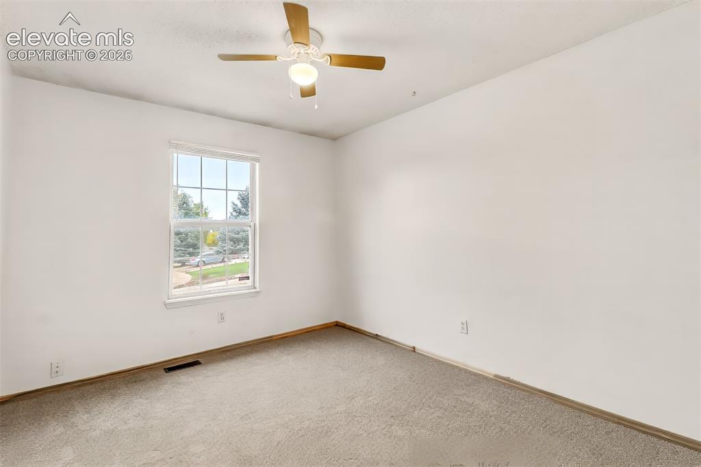 Image 12 of 34: Neutral-toned carpeting, single-hung window with muntins, and ceiling fan w