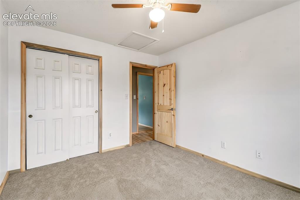 Image 15 of 34: Neutral-toned carpeting, wood-trimmed interior door, sliding closet doors w