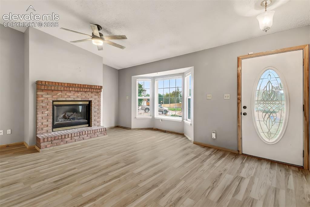 Image 2 of 34: Living area featuring wood-finish flooring, brick fireplace with a hearth,