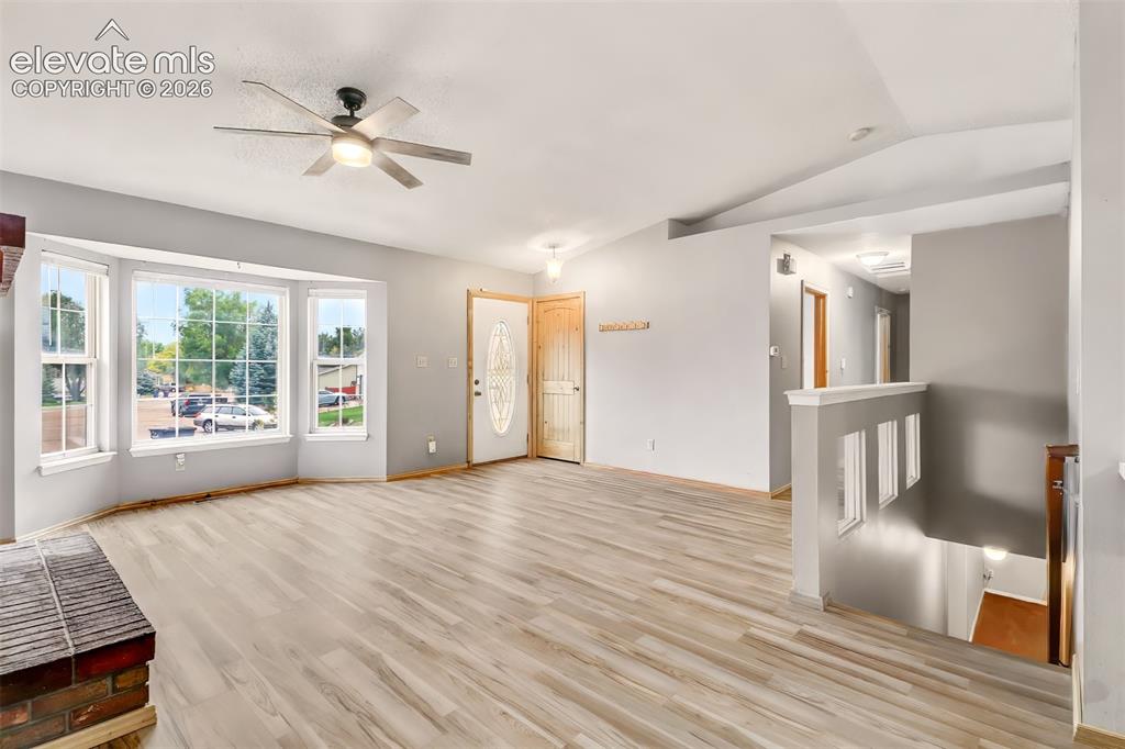 Image 4 of 34: Open interior featuring wood-finish flooring, vaulted ceiling, bay window,