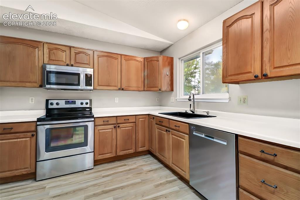Image 6 of 34: Kitchen featuring wood cabinetry, stainless steel appliances, white counter