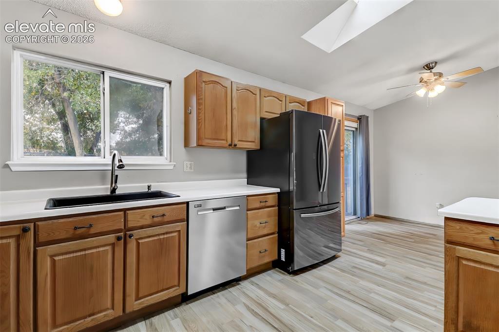 Image 7 of 34: Kitchen featuring natural wood cabinetry, quartz countertops, a skylight, w