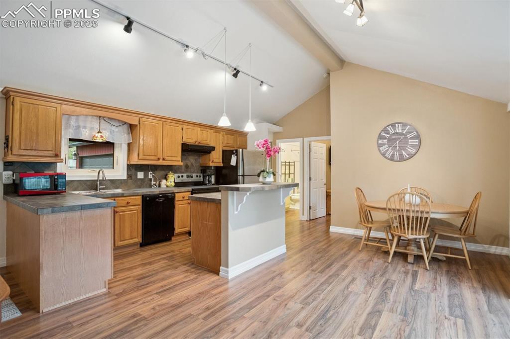 Image 7 of 22: Kitchen with track lighting, backsplash, a kitchen breakfast bar, a center 