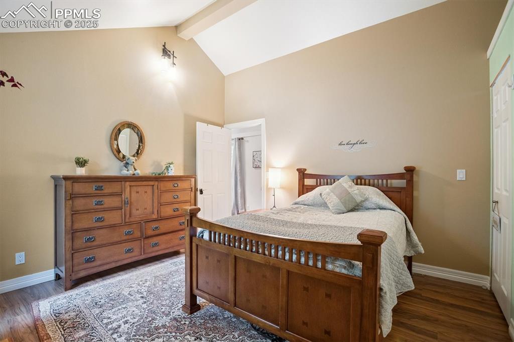 Image 9 of 22: Bedroom with beam ceiling, dark wood-style floors, high vaulted ceiling, an