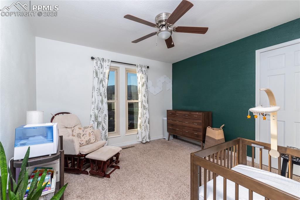 Image 14 of 48: Carpeted bedroom with a crib and ceiling fan