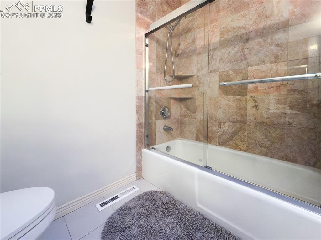 Image 19 of 48: Full bath featuring bath / shower combo with glass door and tile patterned