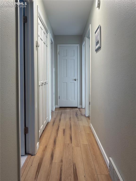Image 20 of 48: Corridor with a textured wall and light wood-style flooring