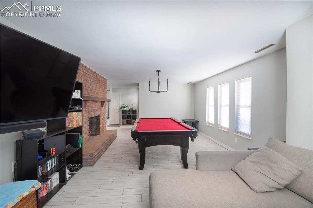 Image 24 of 48: Rec room featuring billiards table, a fireplace, and wood tiled floors