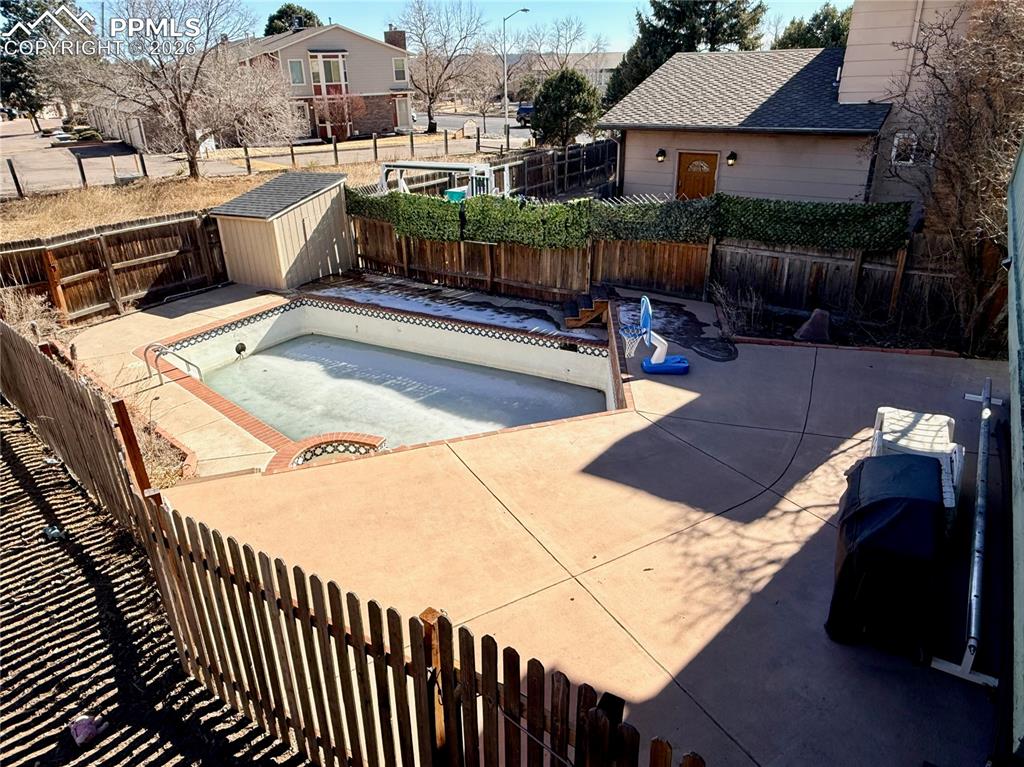 Image 35 of 48: View of pool with a fenced backyard, a storage shed, an empty pool, and pat