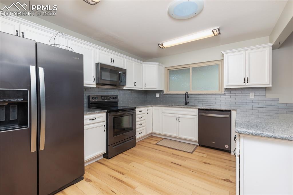 Image 6 of 48: Kitchen with stainless steel appliances, white cabinets, light wood-style f