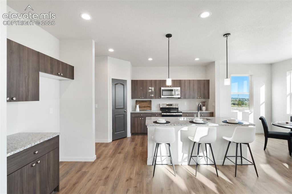 Image 10 of 40: Open-concept kitchen featuring wood-finish cabinetry, a central island with