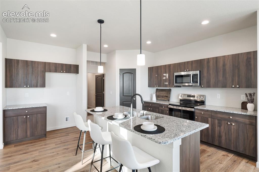 Image 11 of 40: Kitchen featuring wood-finish cabinetry, light-toned countertops, stainless