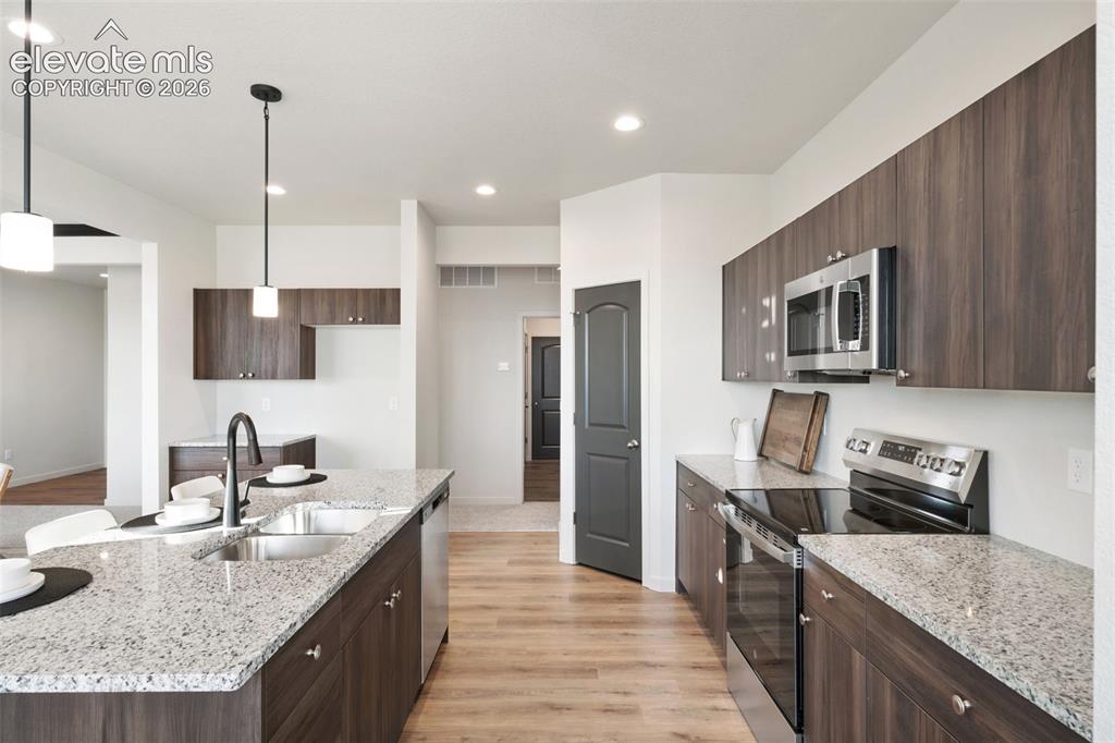 Image 12 of 40: Kitchen featuring wood-finish cabinetry, stainless steel appliances, speckl