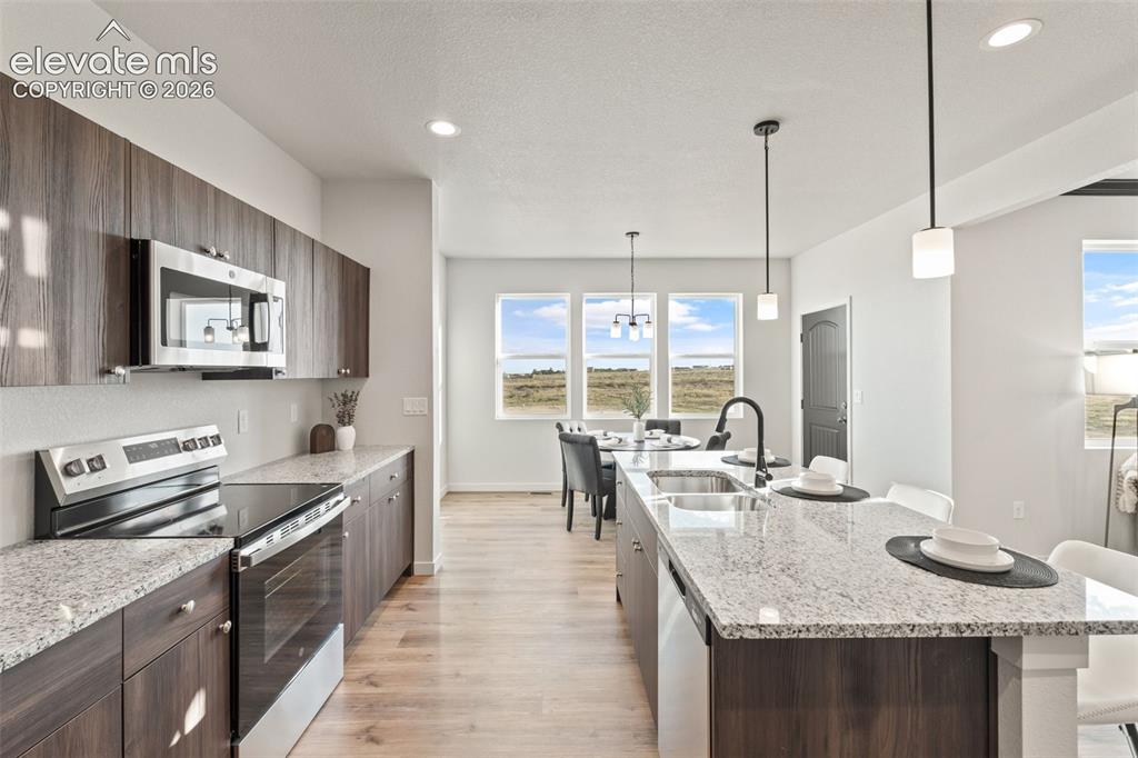 Image 14 of 40: Kitchen featuring wood-finish cabinetry, stainless steel appliances, and li