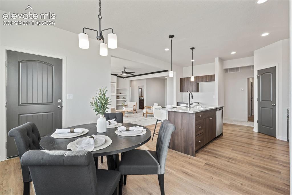 Image 16 of 40: Open-concept dining area with wood-finish flooring, modern chandelier, and 