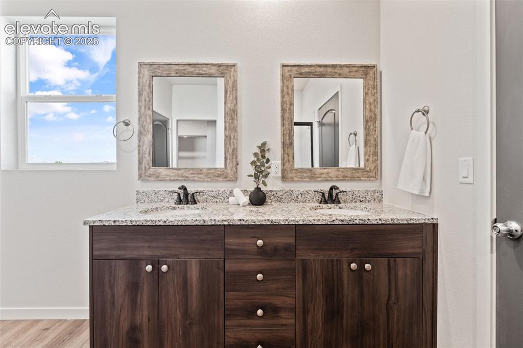 Image 20 of 40: Double vanity with granite countertop, wood-finish cabinetry, dual sinks, a
