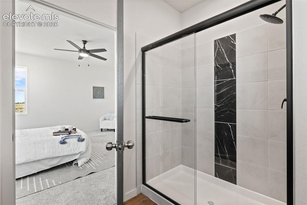 Image 21 of 40: Shower with a sliding glass door, black accent tile, and a rainfall showerh