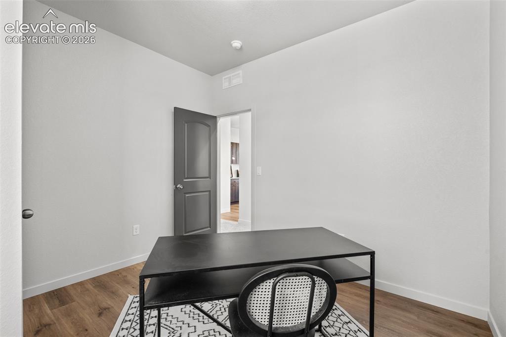 Image 24 of 40: Wood-finish flooring with white baseboards, and a paneled interior door