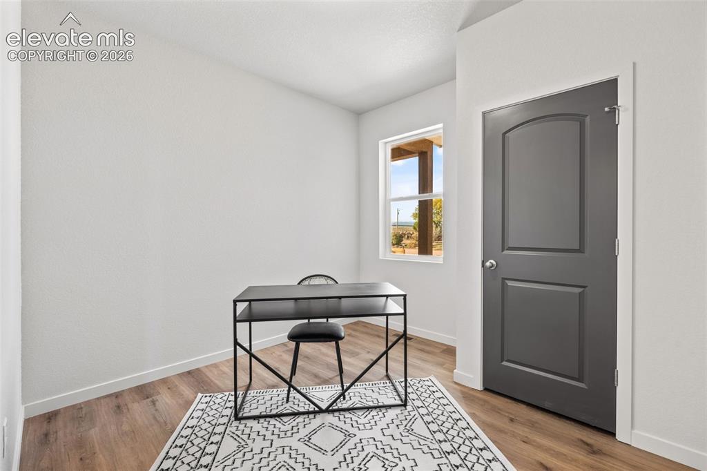 Image 25 of 40: Wood-finish flooring, white painted walls, and a window with natural light