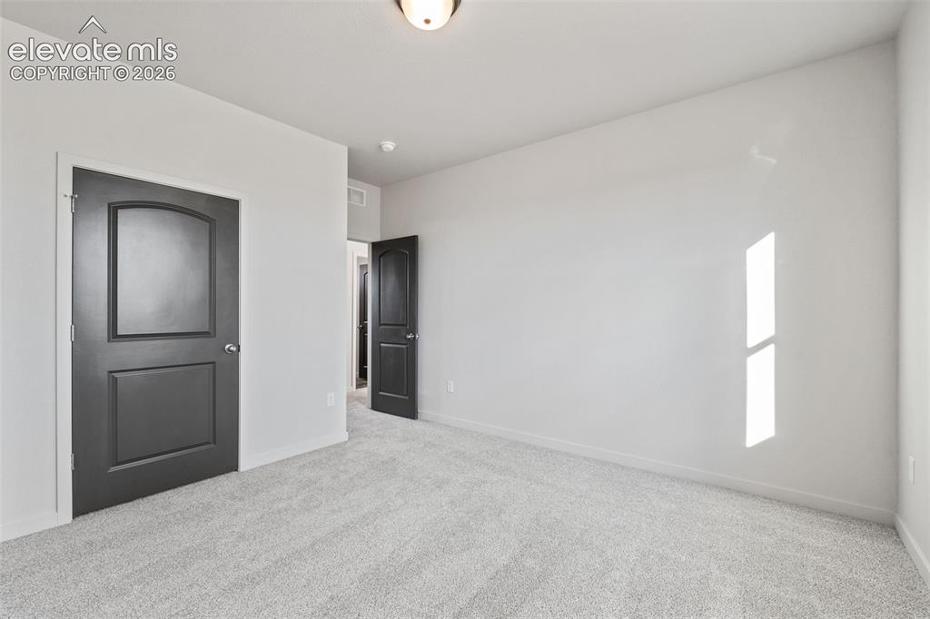 Image 27 of 40: Light gray carpeting, white walls, and dark interior doors