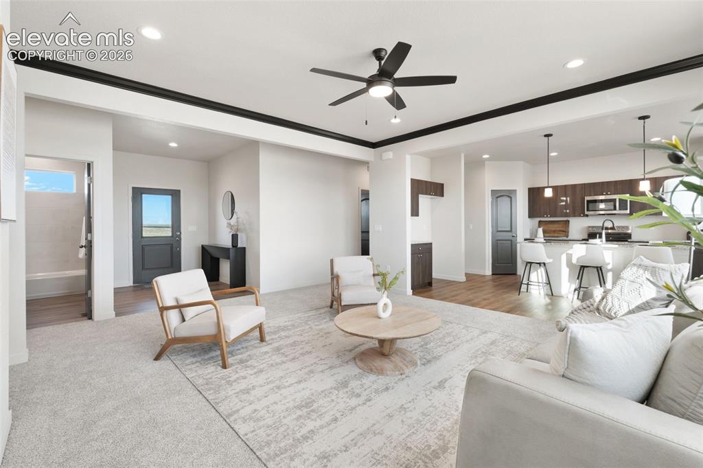 Image 9 of 40: Open-concept living area with recessed lighting, a ceiling fan, and dark tr