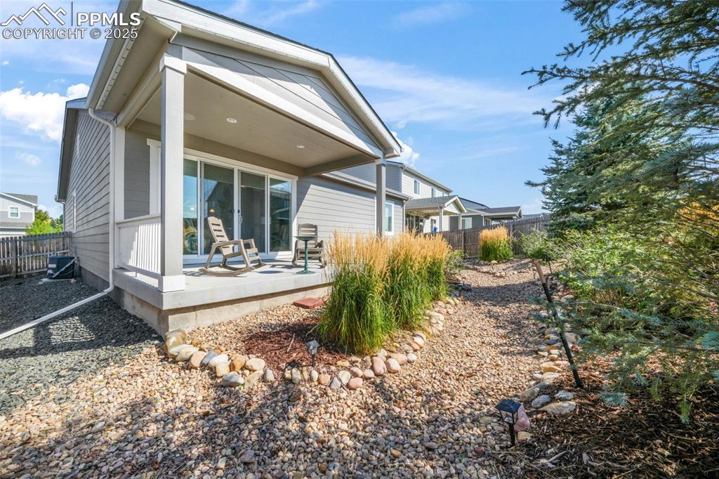 Image 35 of 47: Covered patio, landscaped backyard, privacy fence