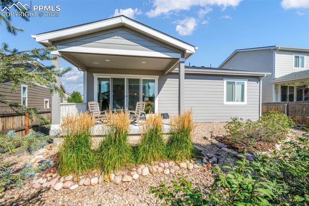 Image 36 of 47: Covered patio, landscaped backyard, privacy fence