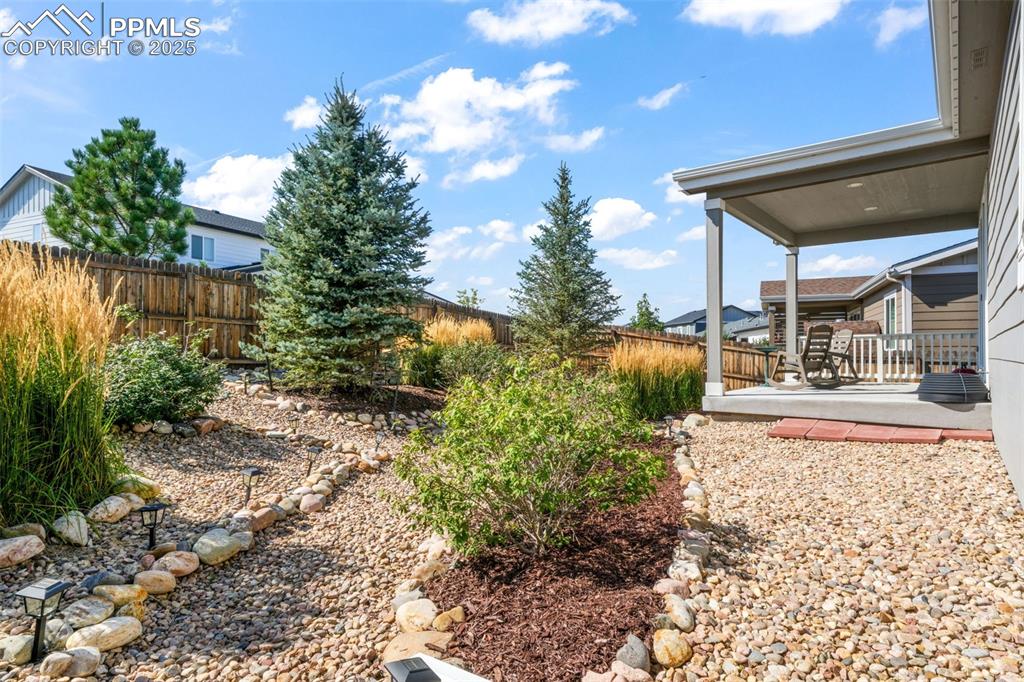 Image 37 of 47: Covered patio, landscaped backyard, privacy fence