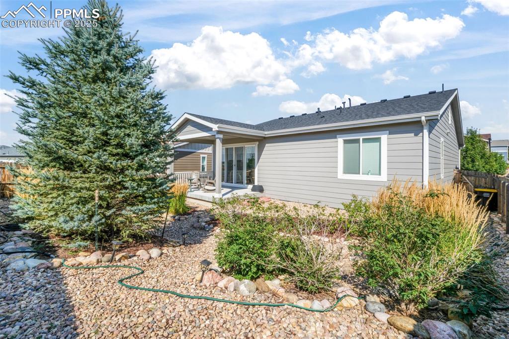 Image 38 of 47: Covered patio, landscaped backyard, privacy fence