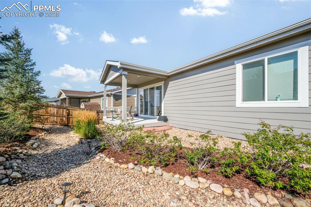 Image 39 of 47: Covered patio, landscaped backyard, privacy fence
