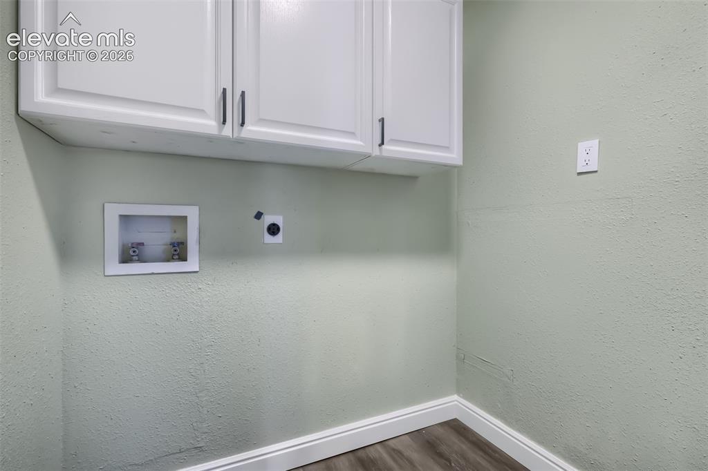 Image 11 of 38: Utility space featuring white cabinetry with dual handles, textured wall fi