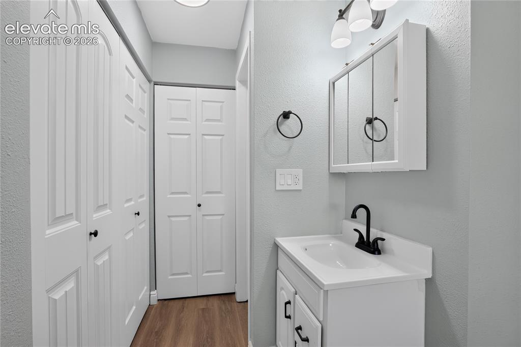 Image 13 of 38: White shaker-style vanity with single basin, black matte faucet, and matchi