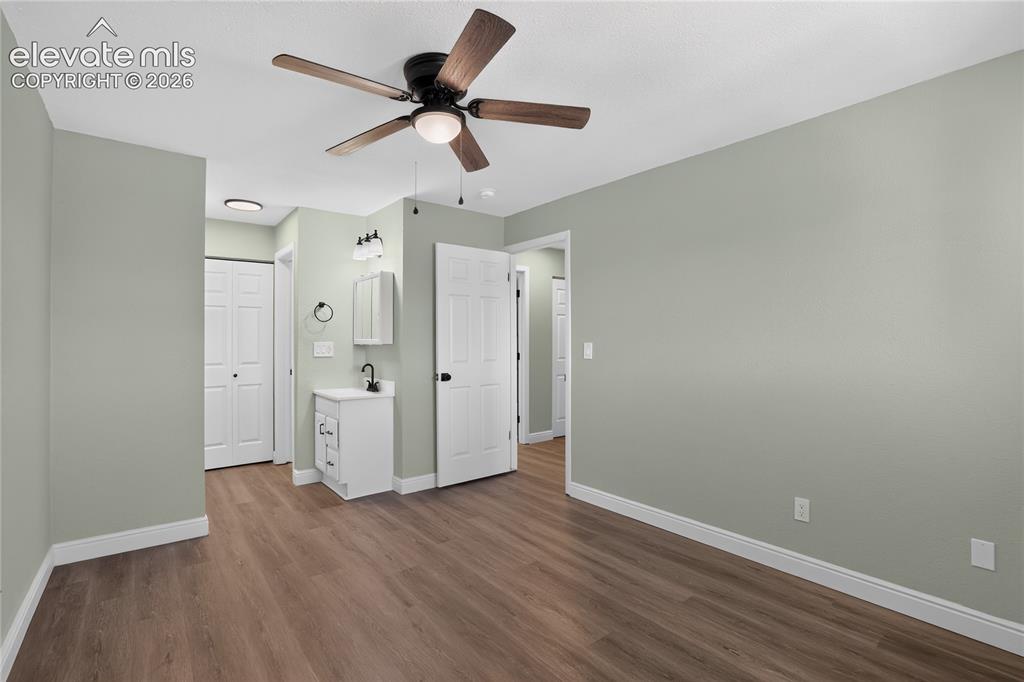 Image 16 of 38: Wood-finish flooring, ceiling fan with integrated lighting, built-in vanity