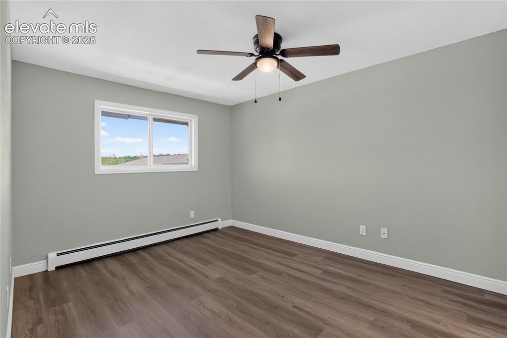 Image 17 of 38: Wood-finish flooring, white trim, a single window, and a ceiling fan with i