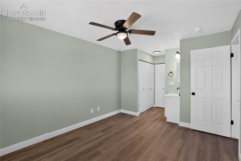 Image 20 of 38: Wood-finish flooring, ceiling fan with light fixture, light green wall fini