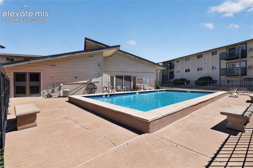 Image 29 of 38: Community swimming pool with a concrete surround and perimeter fencing