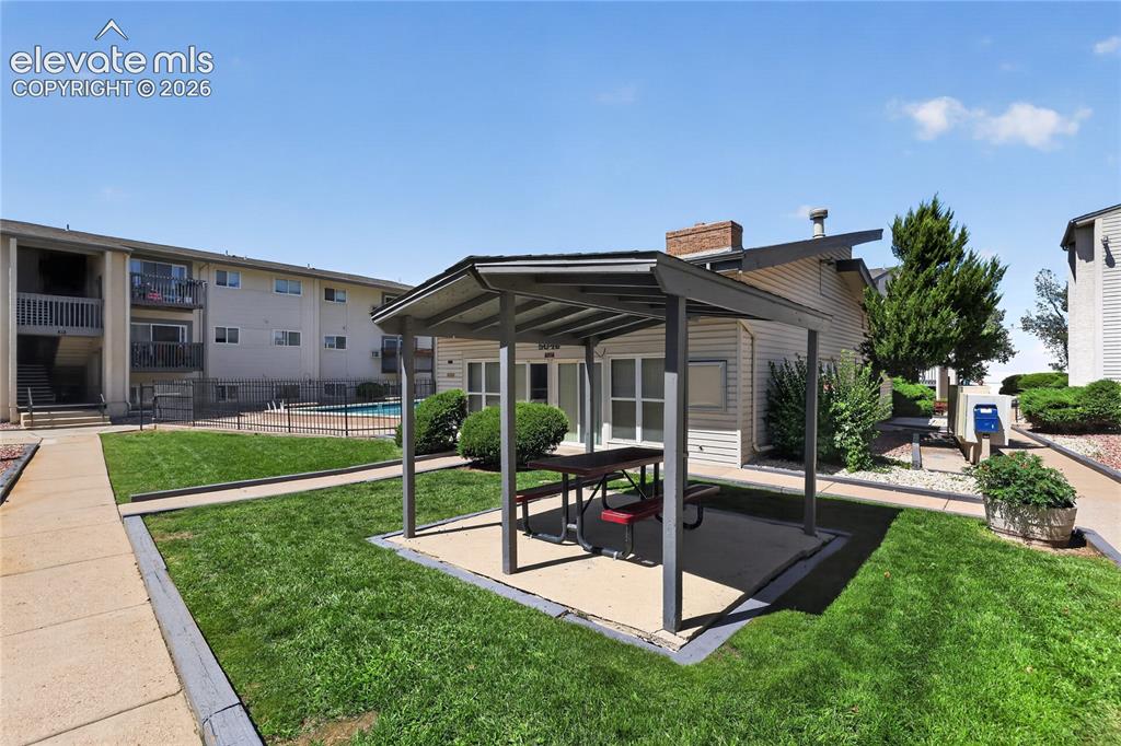 Image 32 of 38: Community courtyard with a covered patio area and manicured lawn