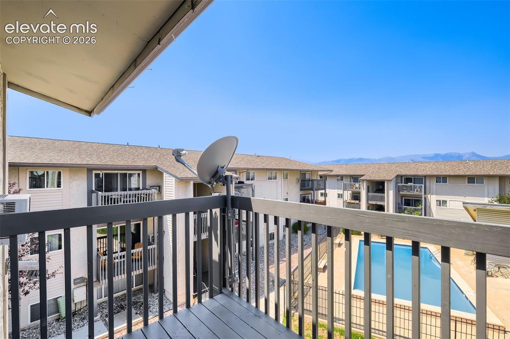 Image 35 of 38: Private balcony with composite decking and metal railing overlooking a comm