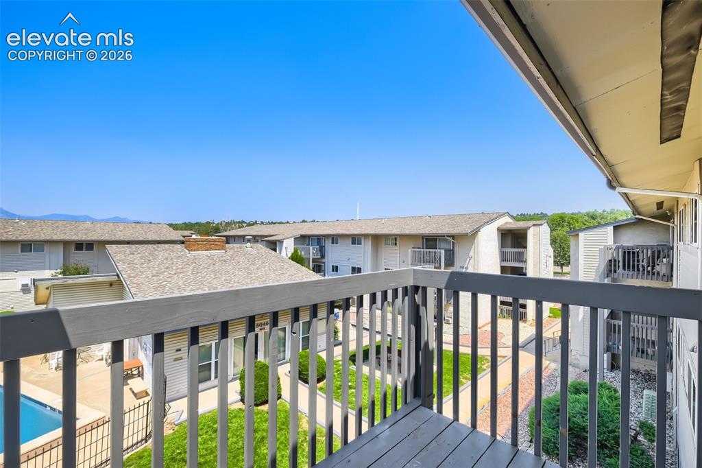 Image 37 of 38: Balcony with wood-finish railing overlooking a courtyard with manicured law