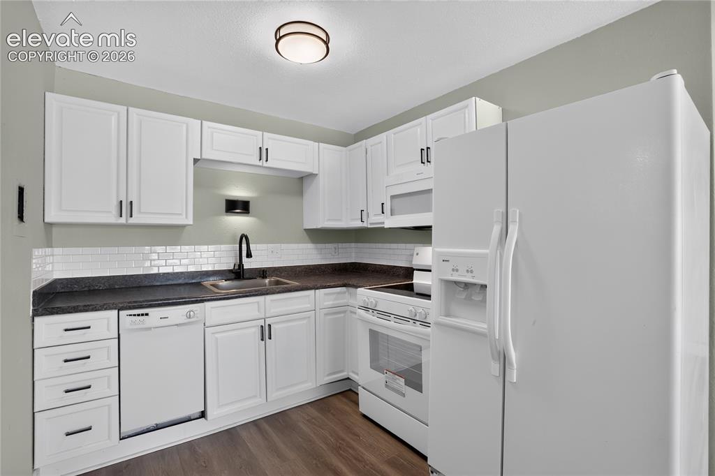 Image 9 of 38: Kitchen featuring white cabinetry, dark countertops, subway tile backsplash