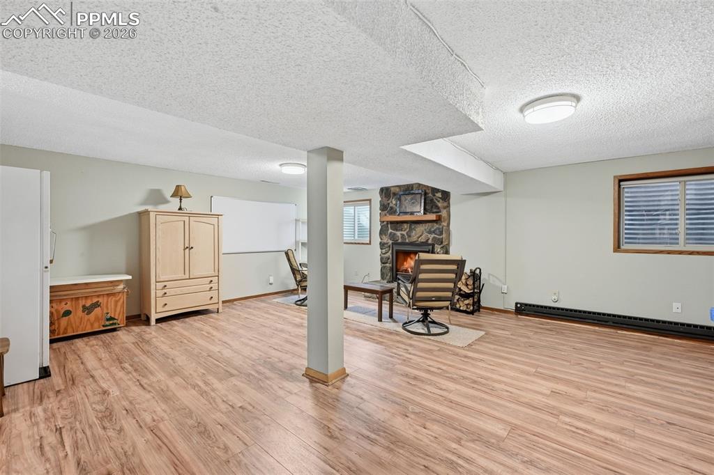 Image 35 of 49: Large basement family room with wood burning fireplace insert.  The large F